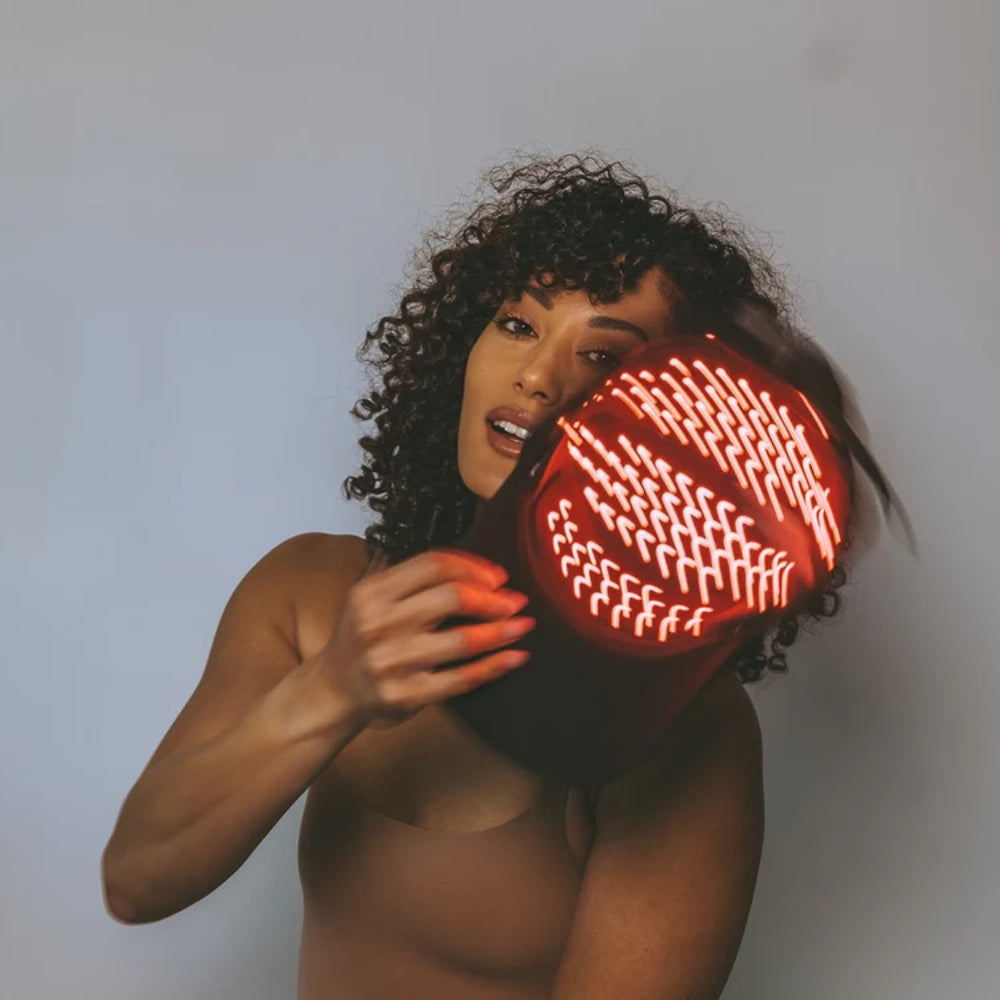 Woman holding a red traffic light against her face on a plain background